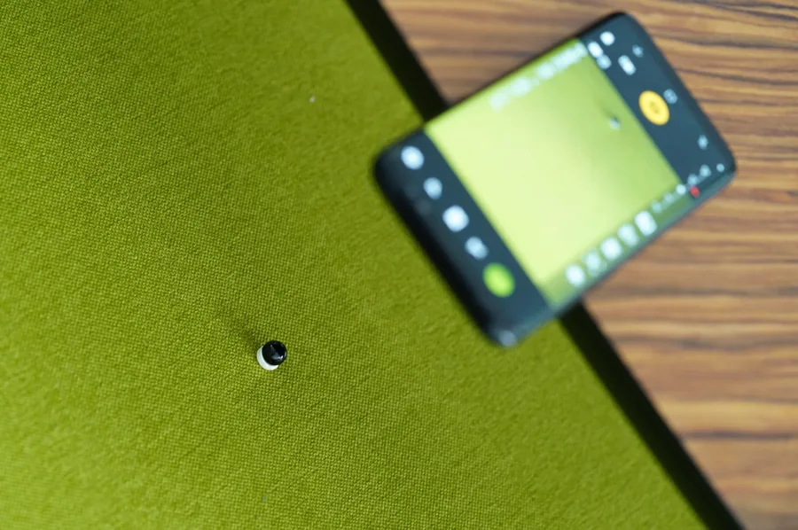 Fixed phone camera facing green fabric with a reflective calibration sphere in frame